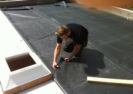 A roofer trimming the edge of an EPDM membrane on a flat roof, by GMG Roof Experts in the Hillingdon area