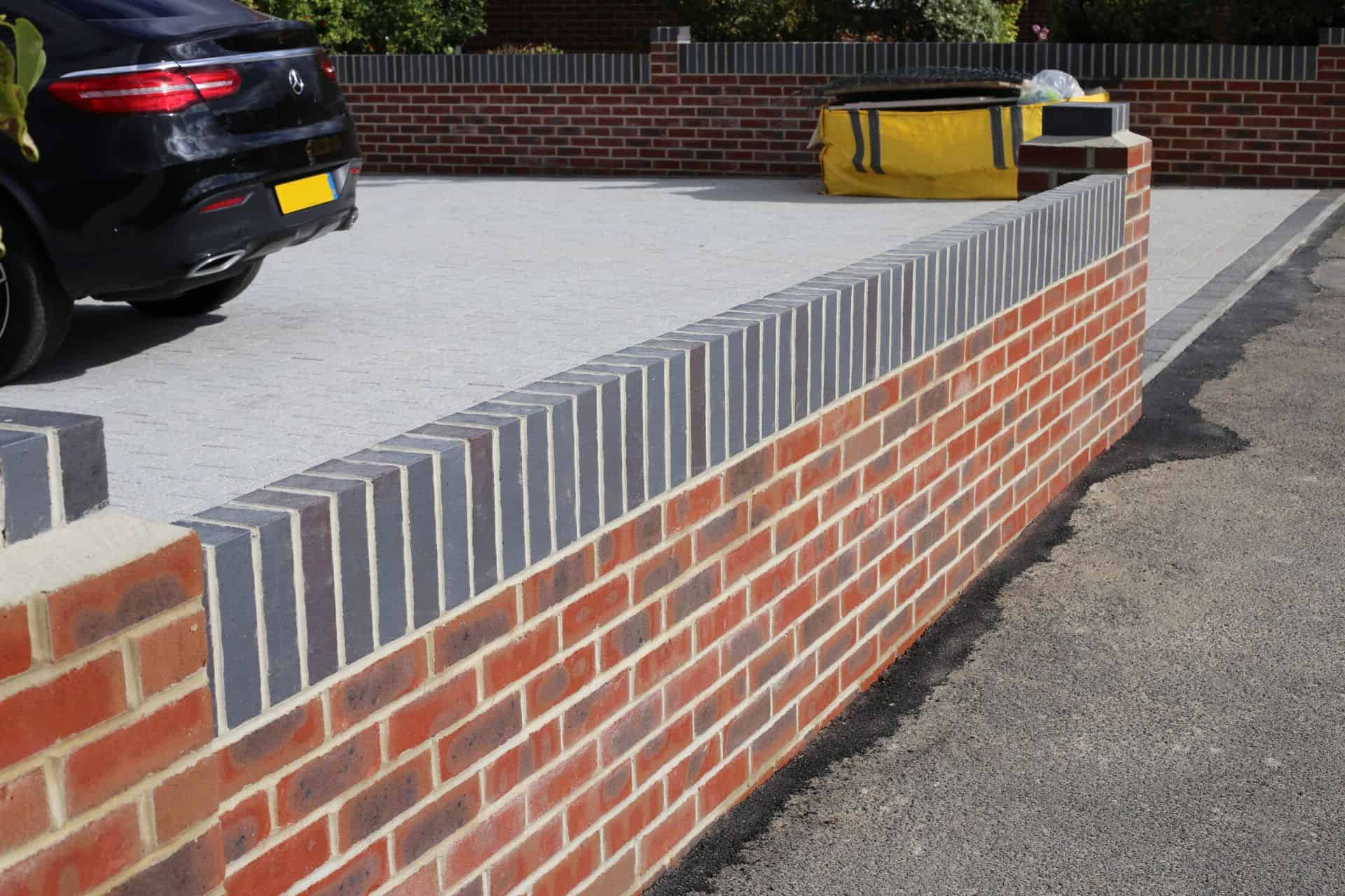 A newly built red and blue brick boundary wall with soldier course coping, by GMG Roof Experts covering Hillingdon