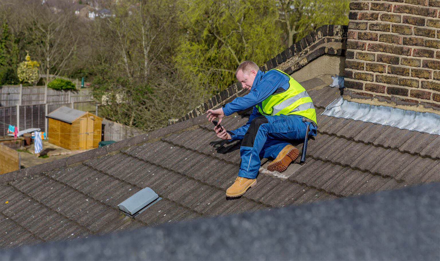 GMG Roof Experts surveyor inspecting a tiled roof and taking photographs, roof inspection and survey across the London Borough of Hillingdon
