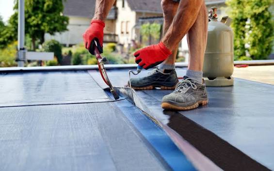 A roofer torching down a bituminous felt membrane on a flat roof, flat roof services by GMG Roof Experts across the London Borough of Hillingdon