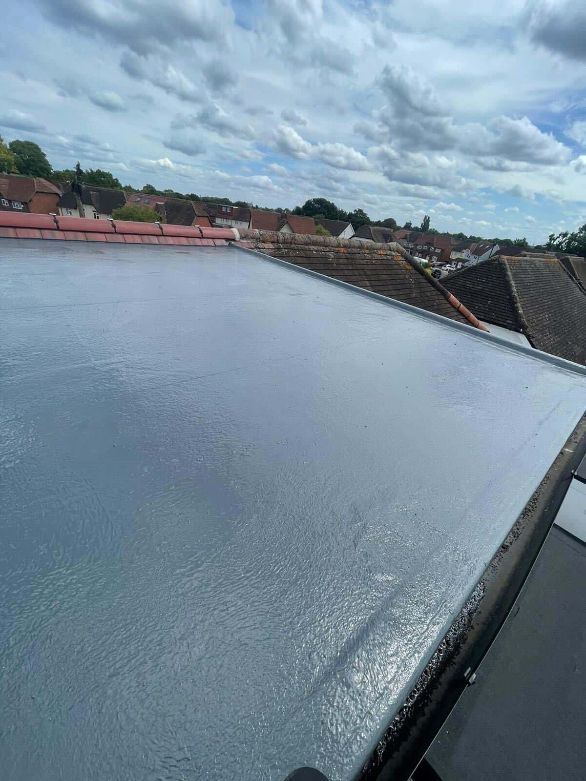 A grey GRP flat roof against a lichen-covered tiled roof, laminate work by GMG Roof Experts in the Hillingdon area